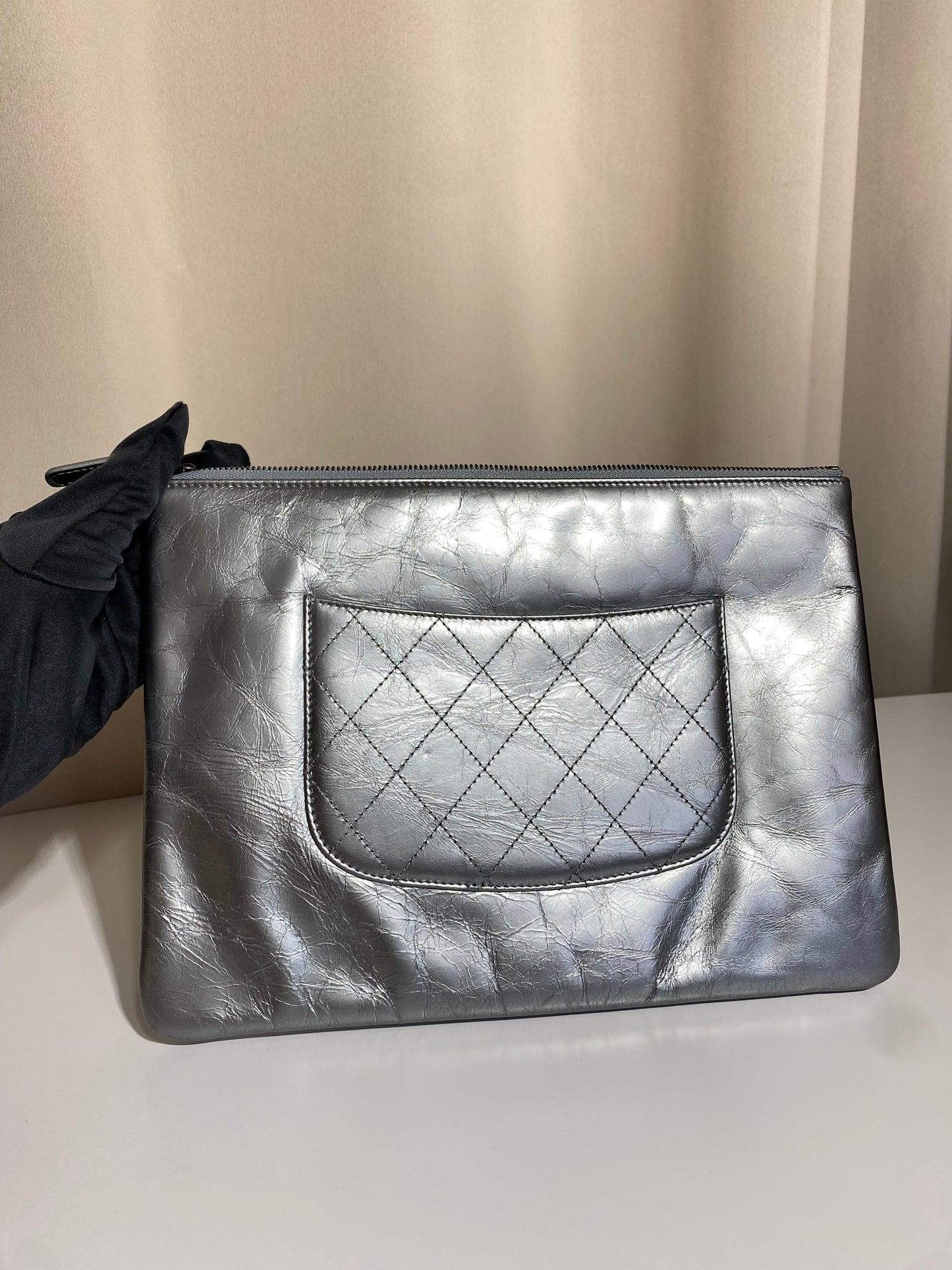 Pochette Chanel O Case Clutch en cuir de veau argent métallisé avec logo chaîne dorée et ruthénium – Très bon état d’occasion – Héritage du Luxe