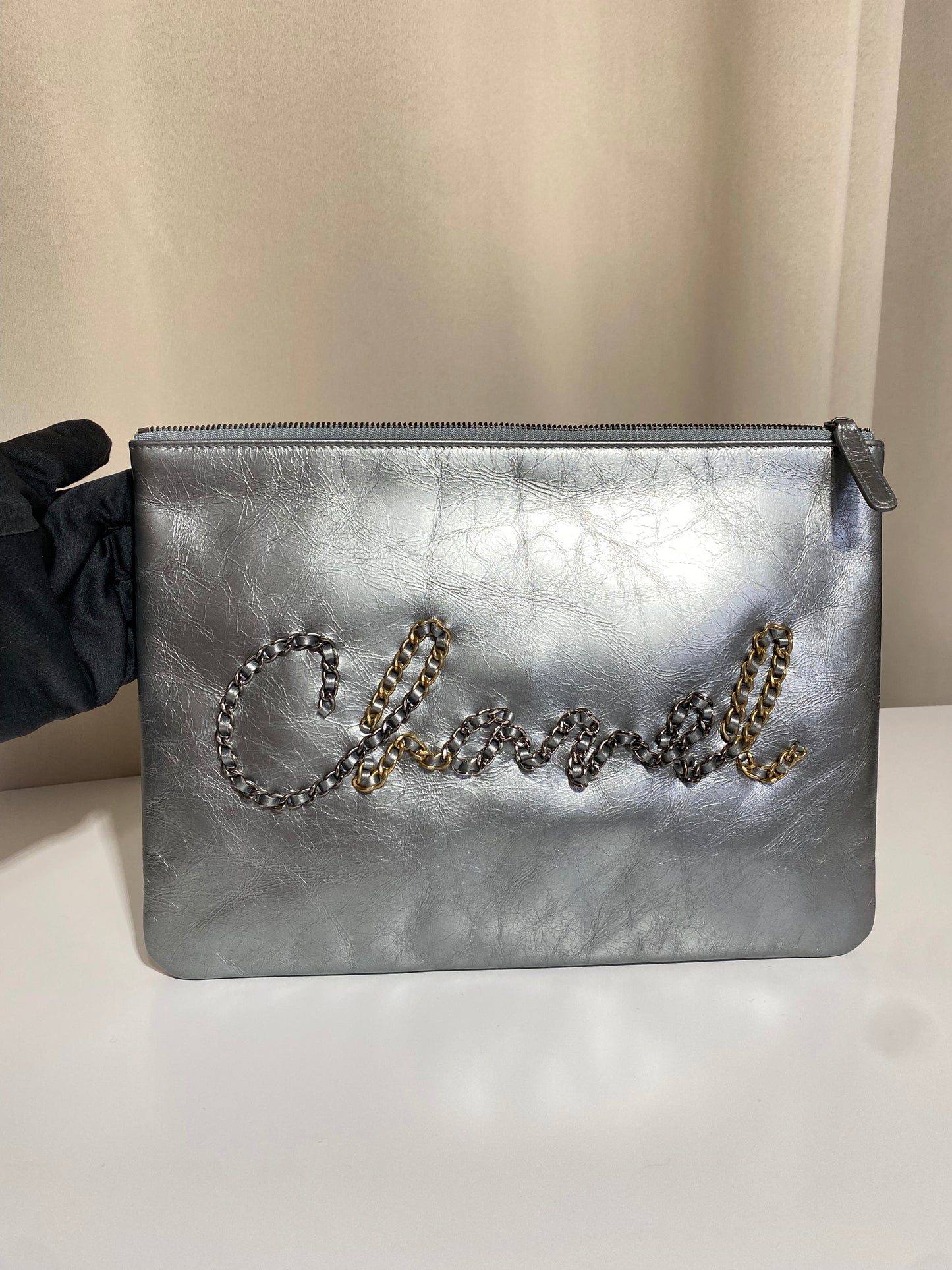 Pochette Chanel O Case Clutch en cuir de veau argent métallisé avec logo chaîne dorée et ruthénium – Très bon état d’occasion – Héritage du Luxe