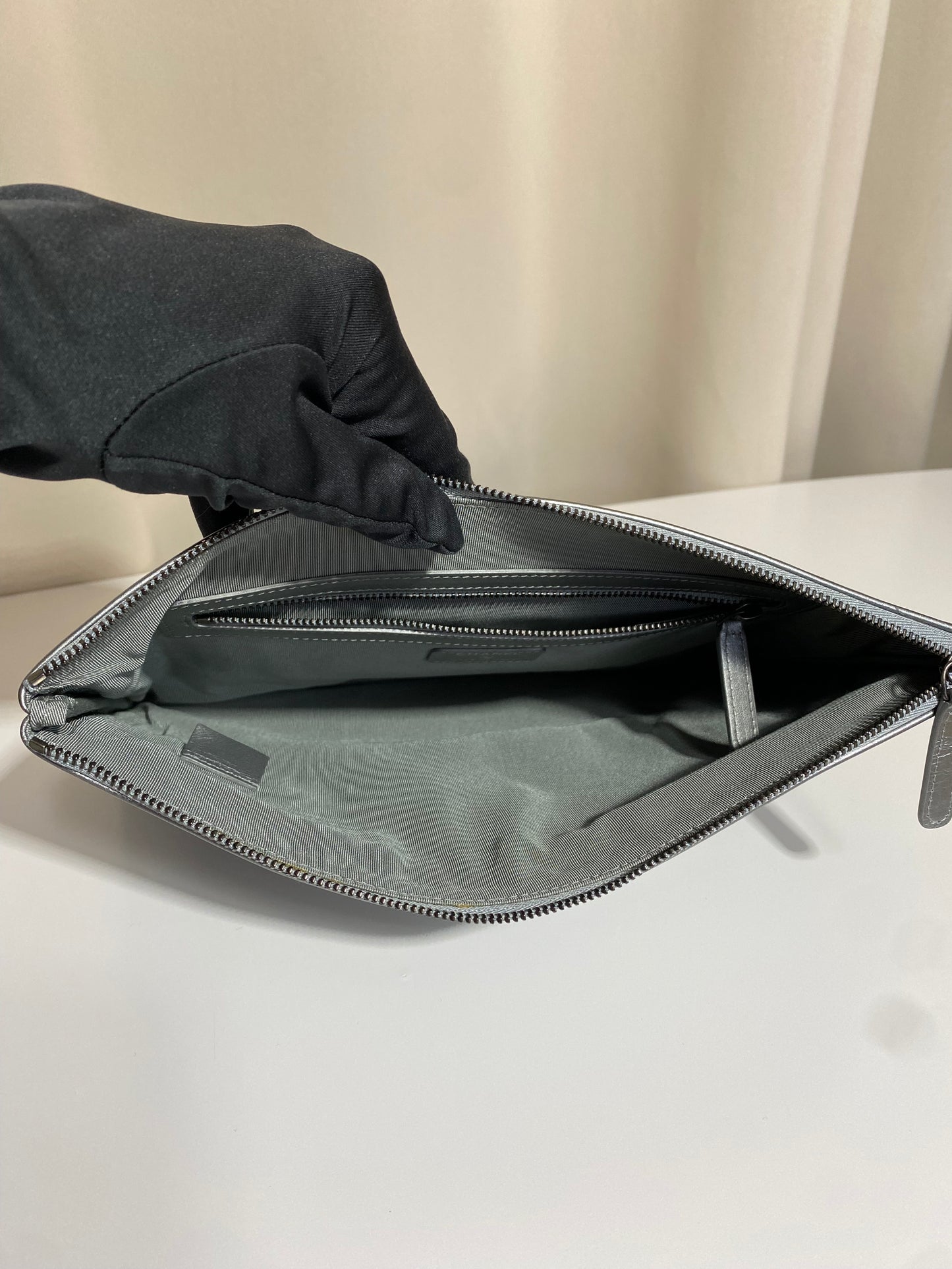Pochette Chanel O Case Clutch en cuir de veau argent métallisé avec logo chaîne dorée et ruthénium – Très bon état d’occasion – Héritage du Luxe