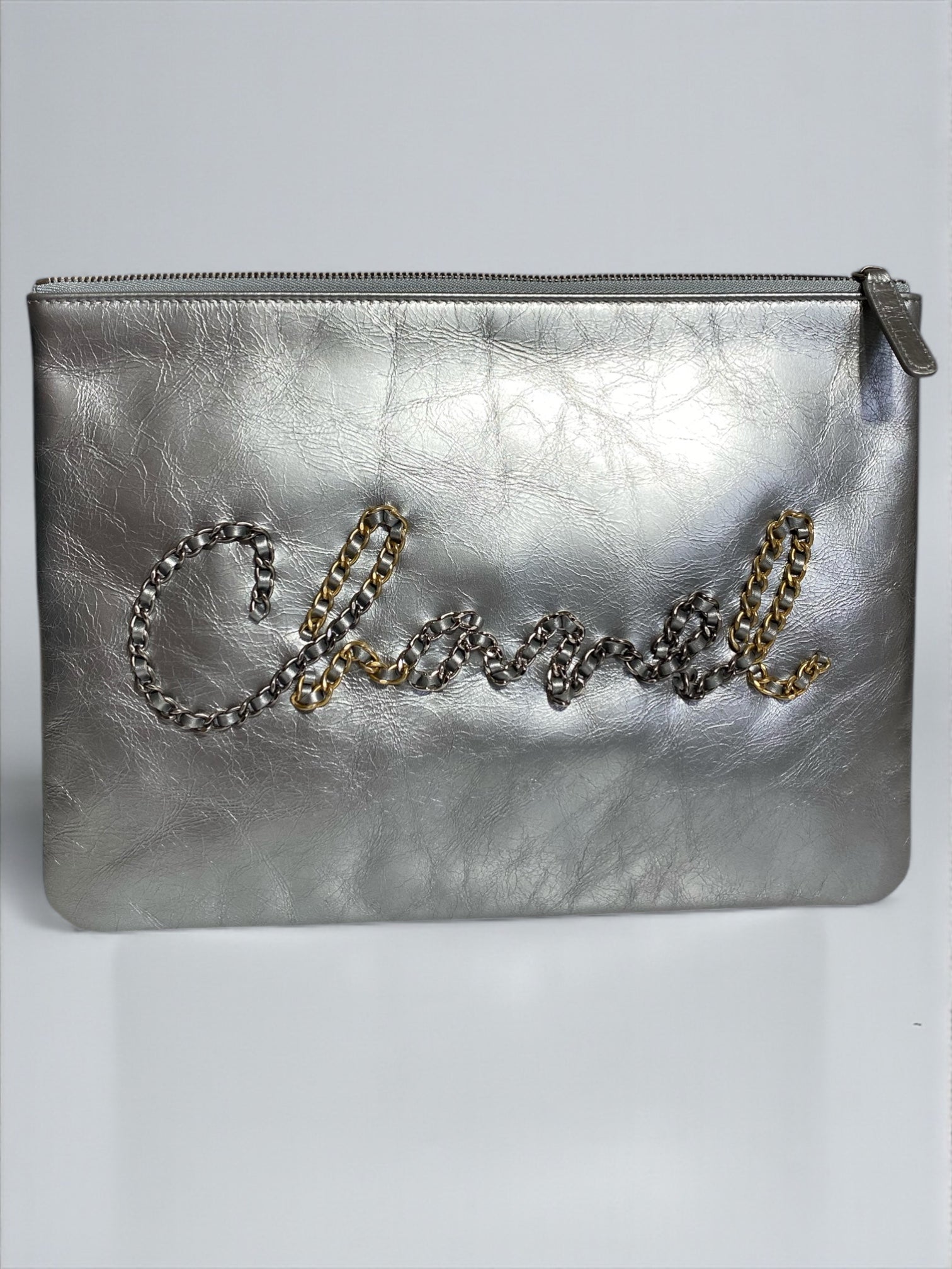 Pochette Chanel O Case Clutch en cuir de veau argent métallisé avec logo chaîne dorée et ruthénium – Très bon état d’occasion – Héritage du Luxe