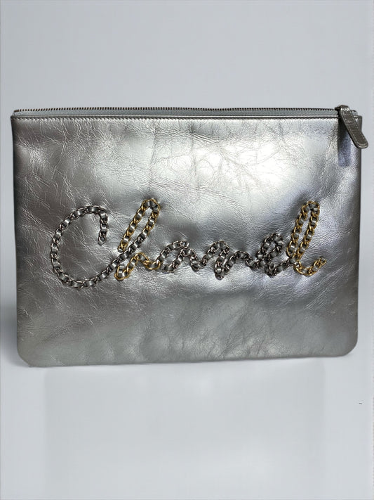 Pochette Chanel O Case Clutch en cuir de veau argent métallisé avec logo chaîne dorée et ruthénium – Très bon état d’occasion – Héritage du Luxe