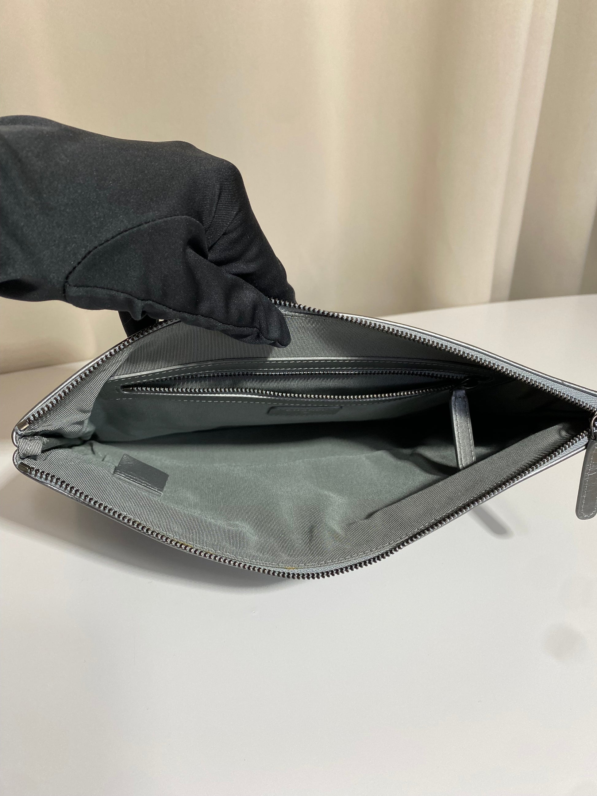 Pochette Chanel O Case Clutch en cuir de veau argent métallisé avec logo chaîne dorée et ruthénium – Très bon état d’occasion – Héritage du Luxe