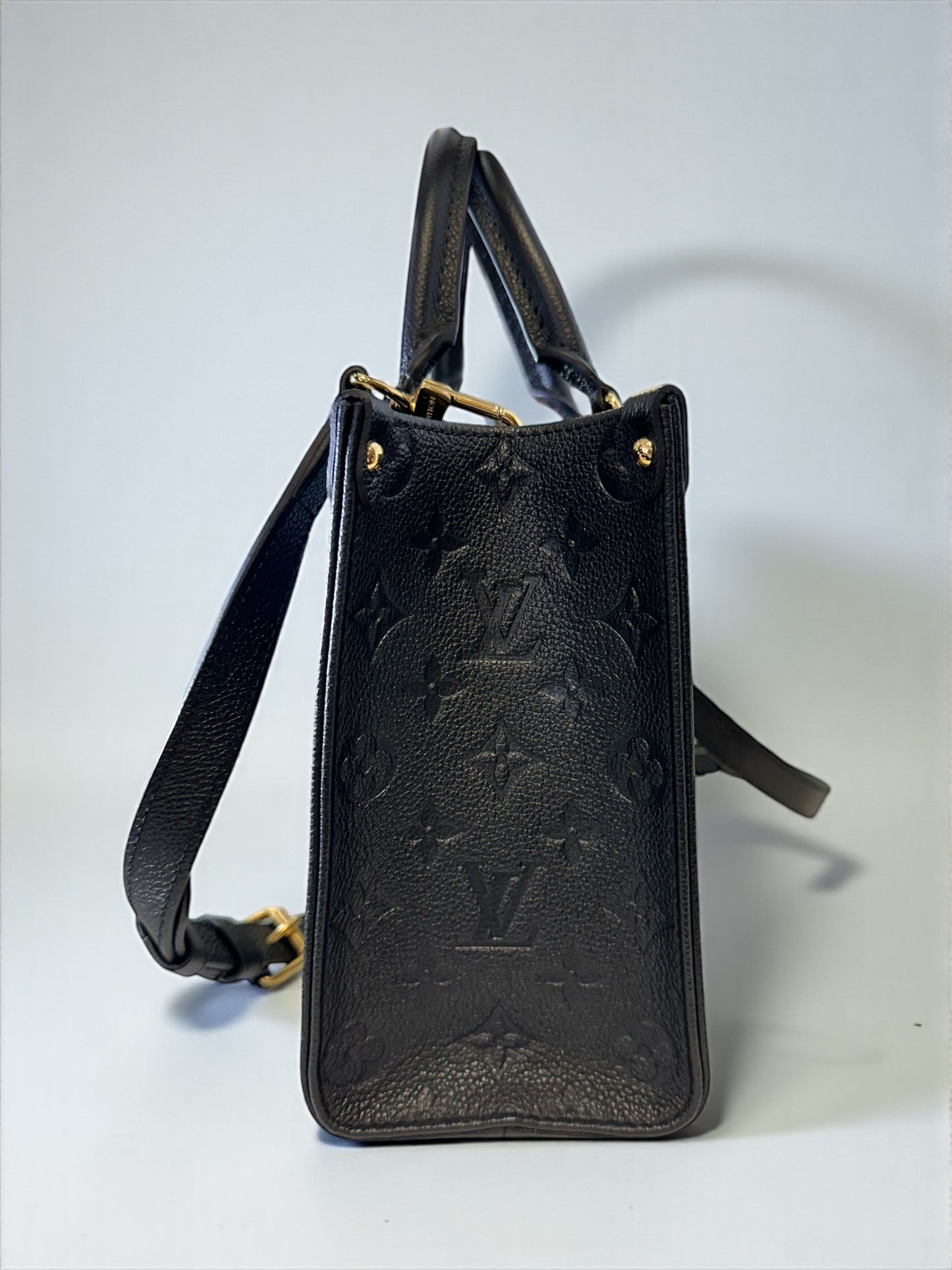 Sac Louis Vuitton OnTheGo PM neuf en cuir Monogram Empreinte noir. Clous dorés, bandoulière ajustable. Authentique & disponible chez Héritage du Luxe.