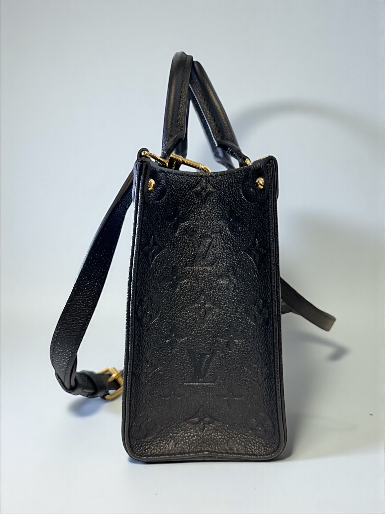 Sac Louis Vuitton OnTheGo PM neuf en cuir Monogram Empreinte noir. Clous dorés, bandoulière ajustable. Authentique & disponible chez Héritage du Luxe.