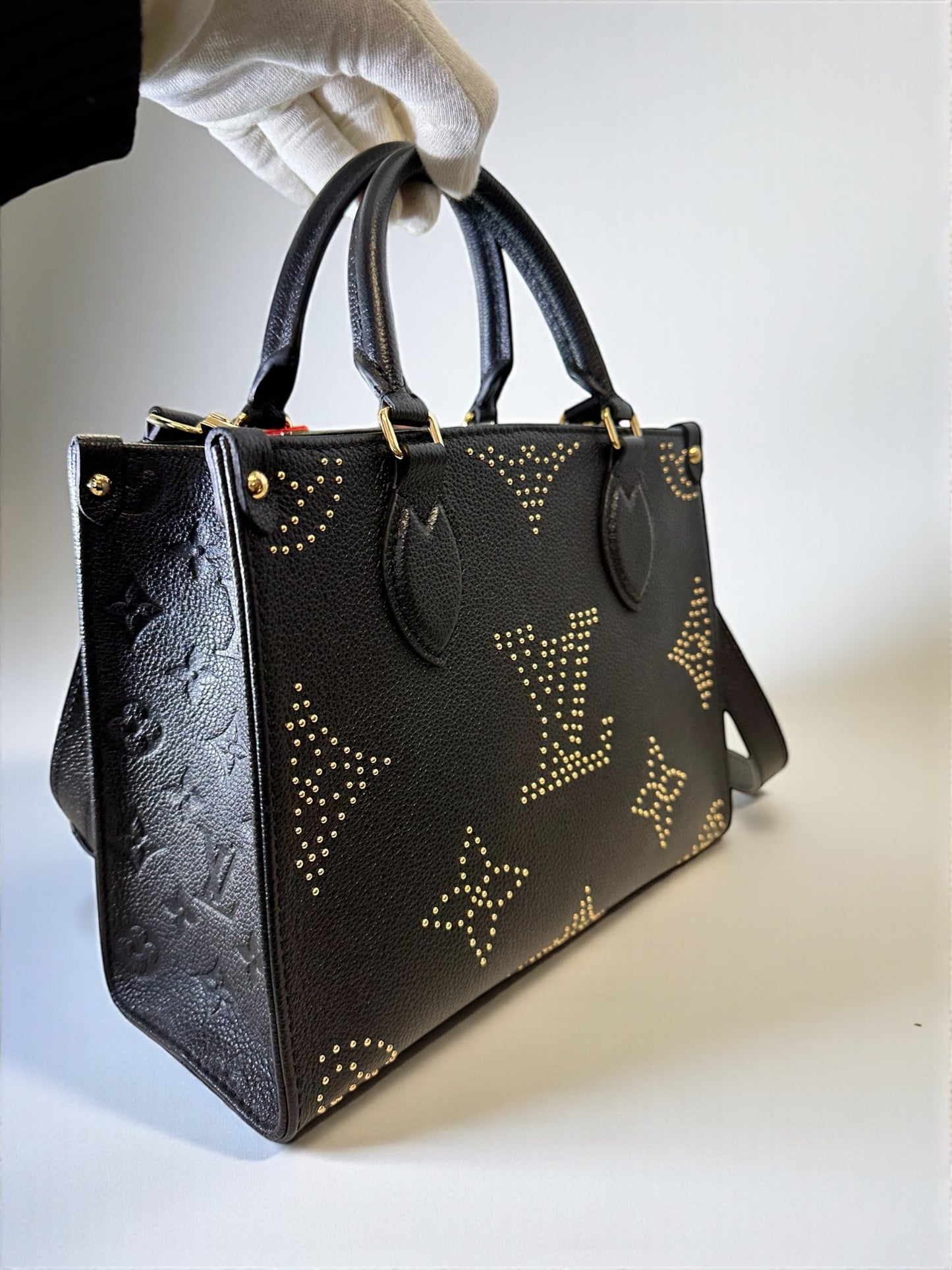 Sac Louis Vuitton OnTheGo PM neuf en cuir Monogram Empreinte noir. Clous dorés, bandoulière ajustable. Authentique & disponible chez Héritage du Luxe.